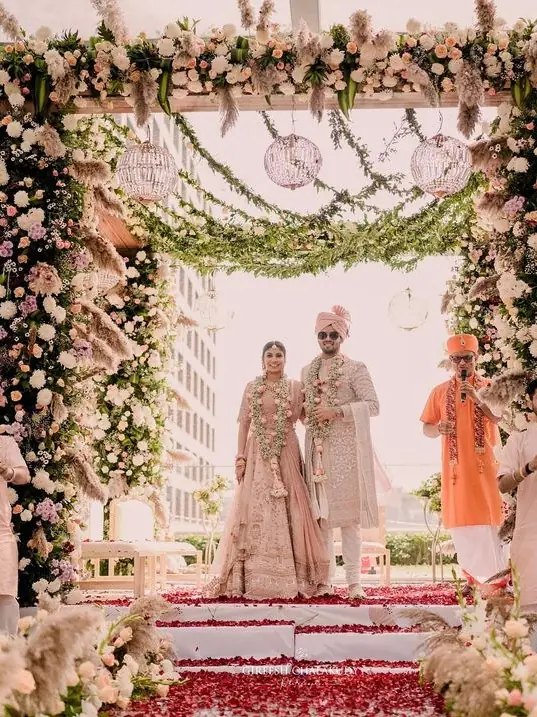 Couple under a floral mandap at a wedding ceremony